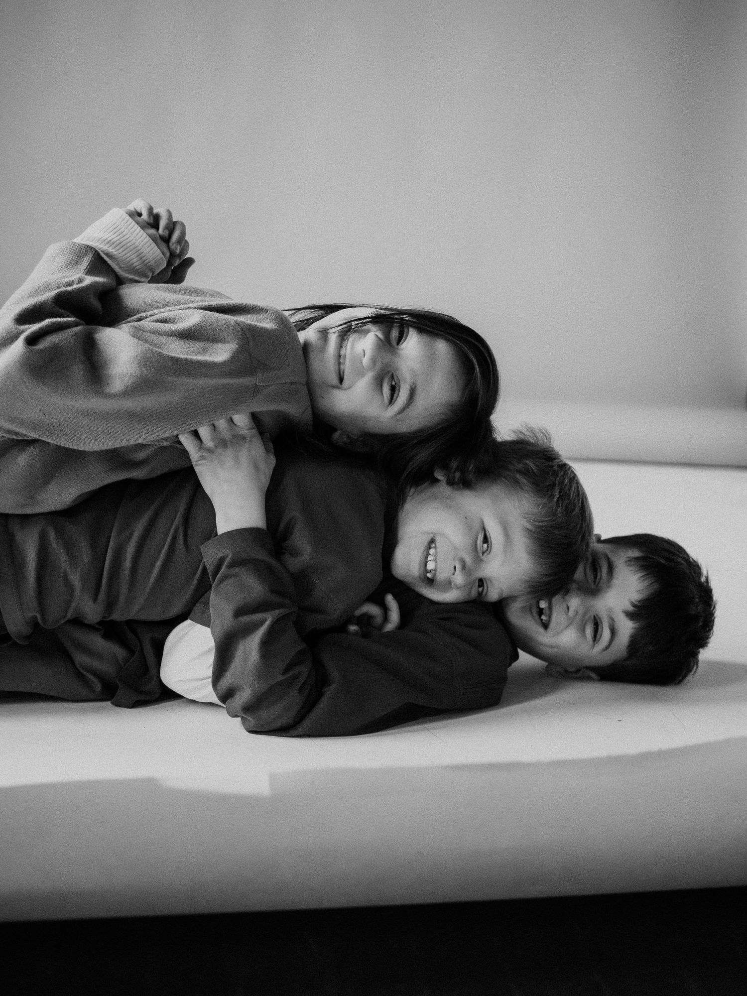 A black and white photo series showing someone lying down in various relaxed poses on a white surface.