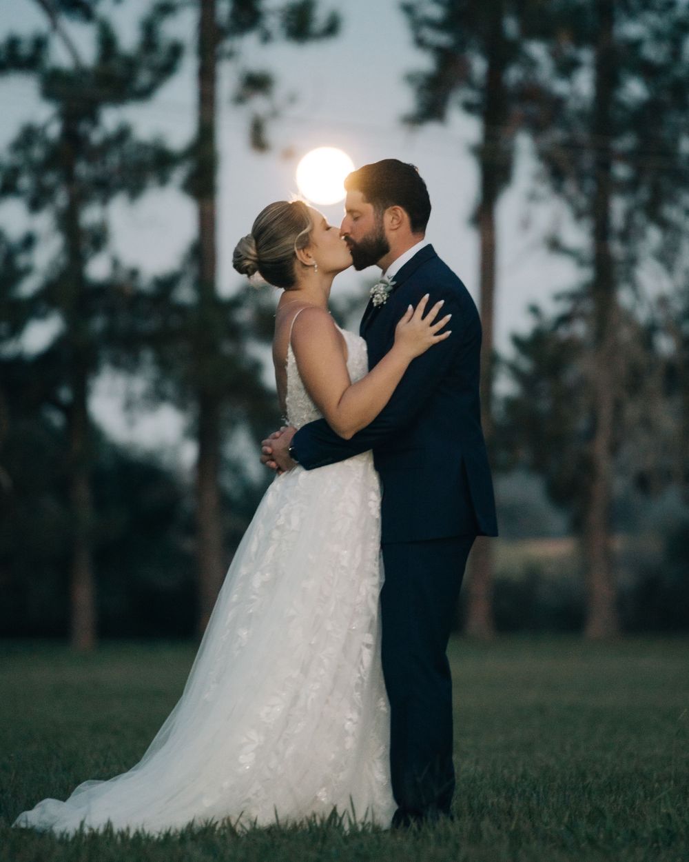 Noivos se beijando ao por do sol em casamento ao ar livre no campo, fotografia de casamento romântica em Minas Gerais