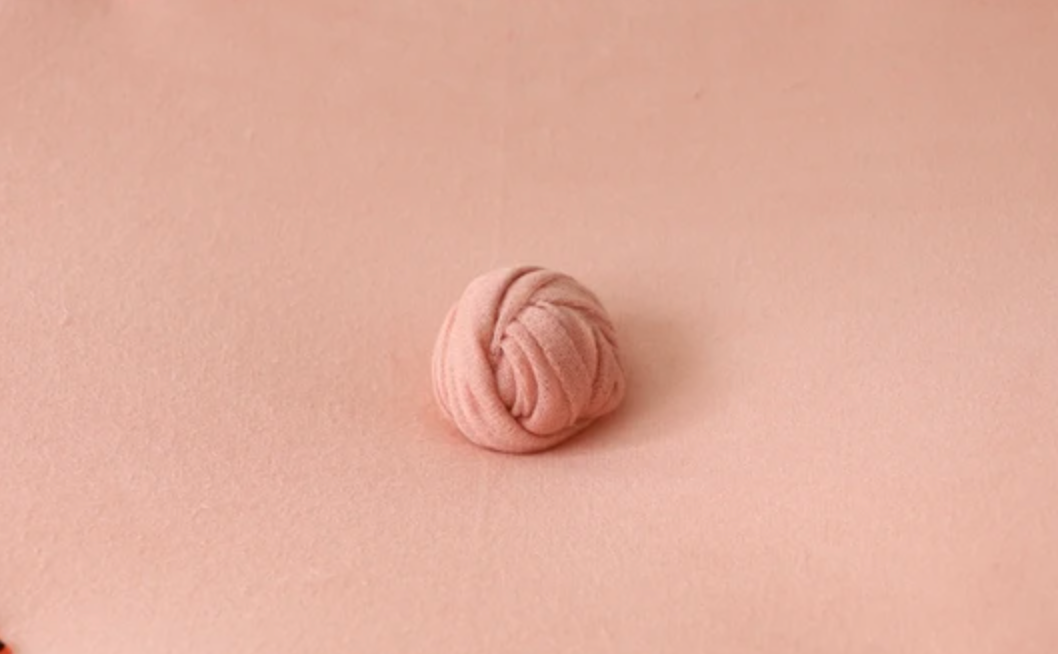 Pink yarn ball photographed against matching pink background.