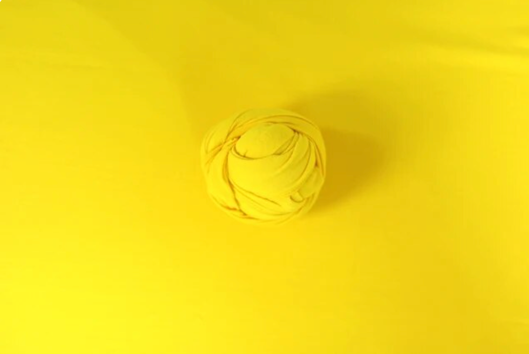 Yellow yarn ball centered on bright yellow background.
