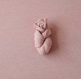 Light pink yarn skein photographed on dusty rose background.
