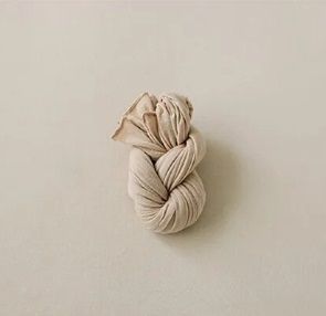 Beige twisted yarn skein displayed on neutral background.