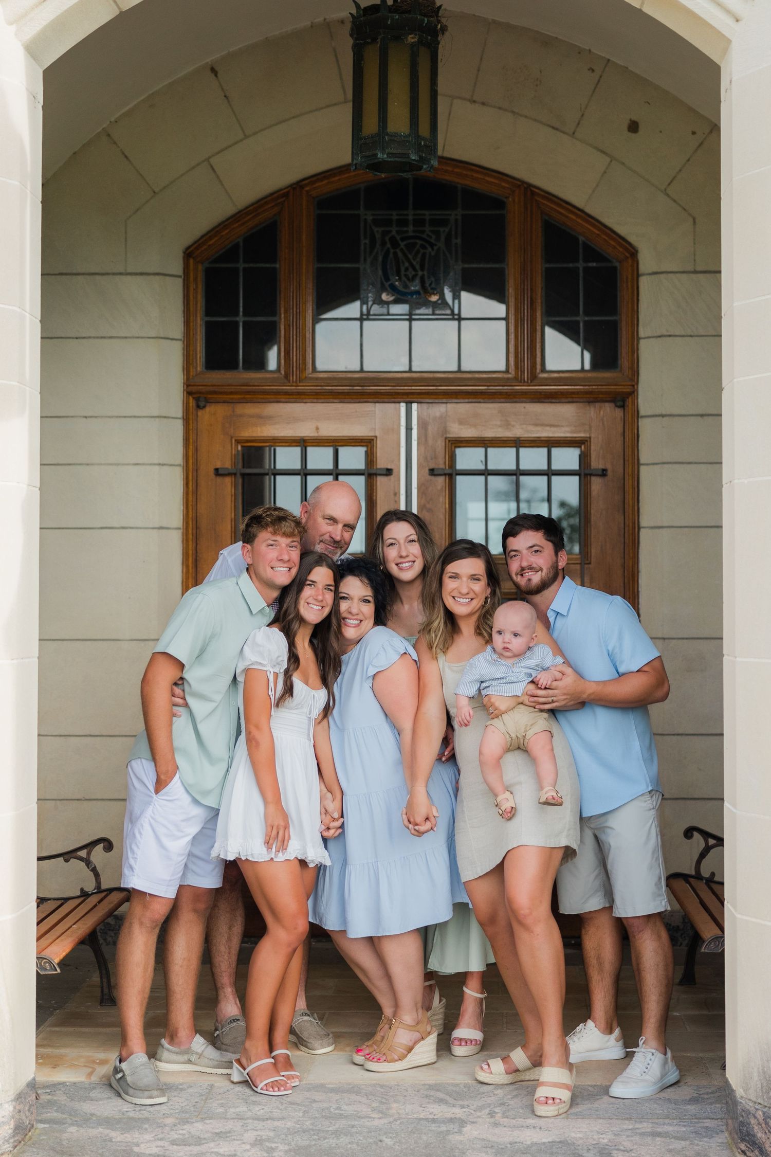 A group poses together in coordinating blue and white outfits under an archway entrance.