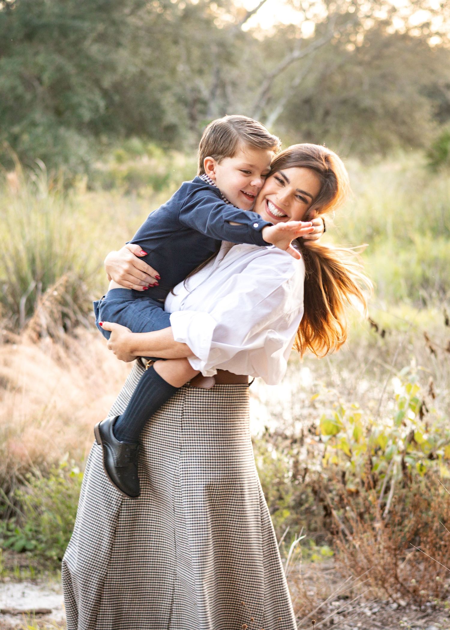 A heartwarming outdoor photoshoot captures tender moments between two people in a natural setting at sunset.