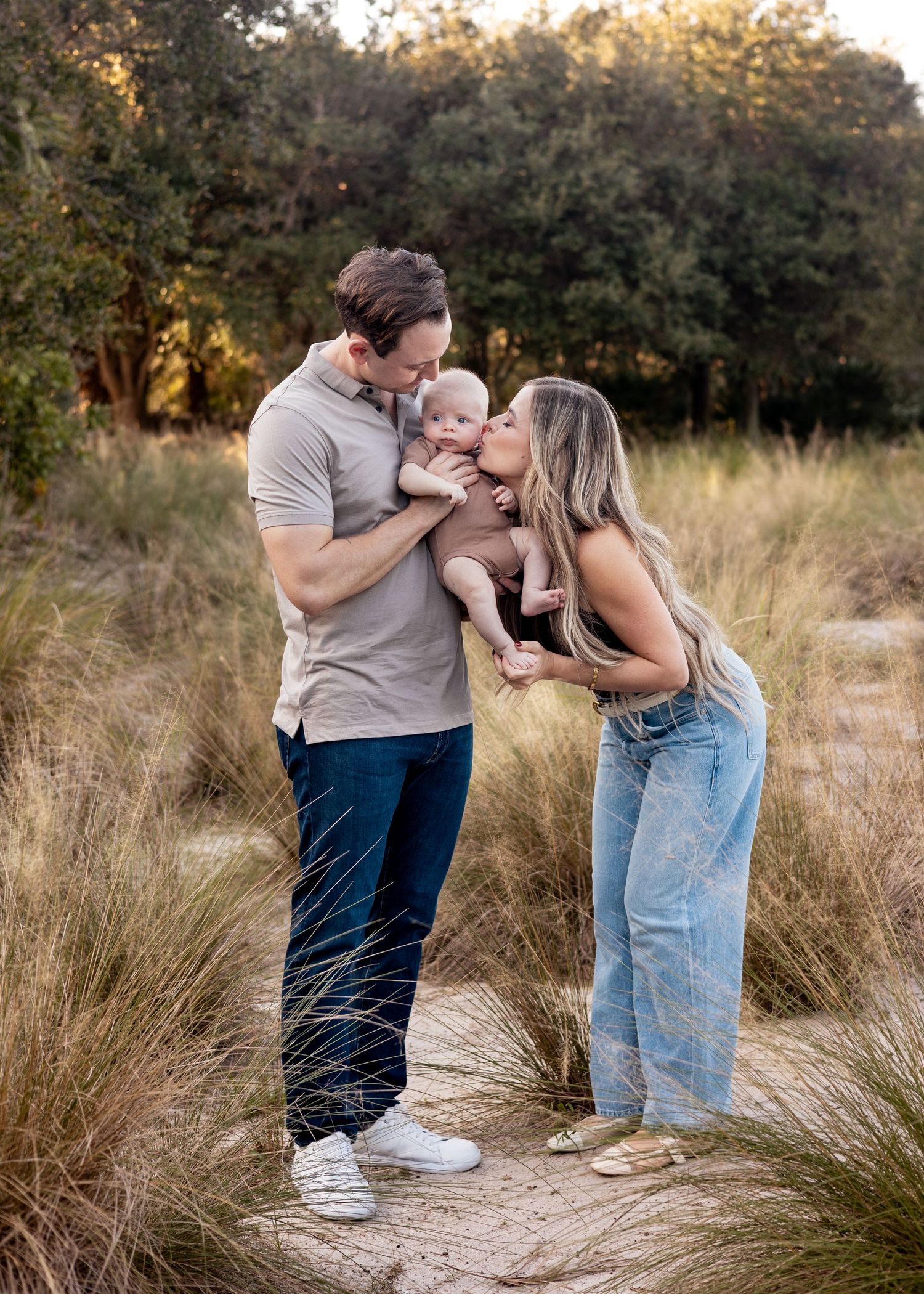 A couple shares tender moments in a field of tall grass during golden hour.
