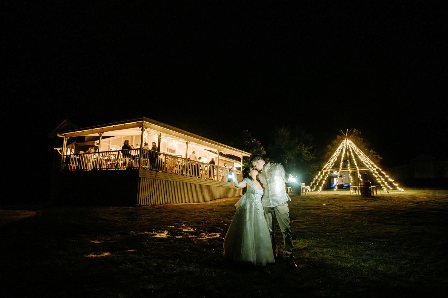 Illuminated wedding venue at night with tent structure glowing against dark sky.
