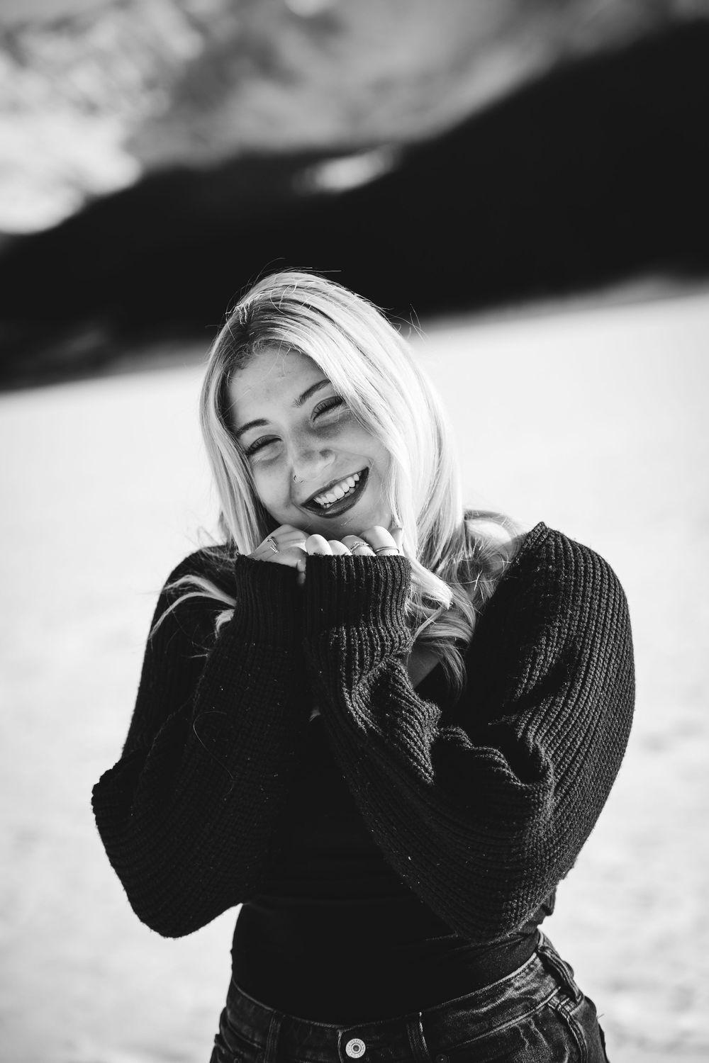 A black and white photo series shows someone in a dark sweater laughing joyfully against a bright background.