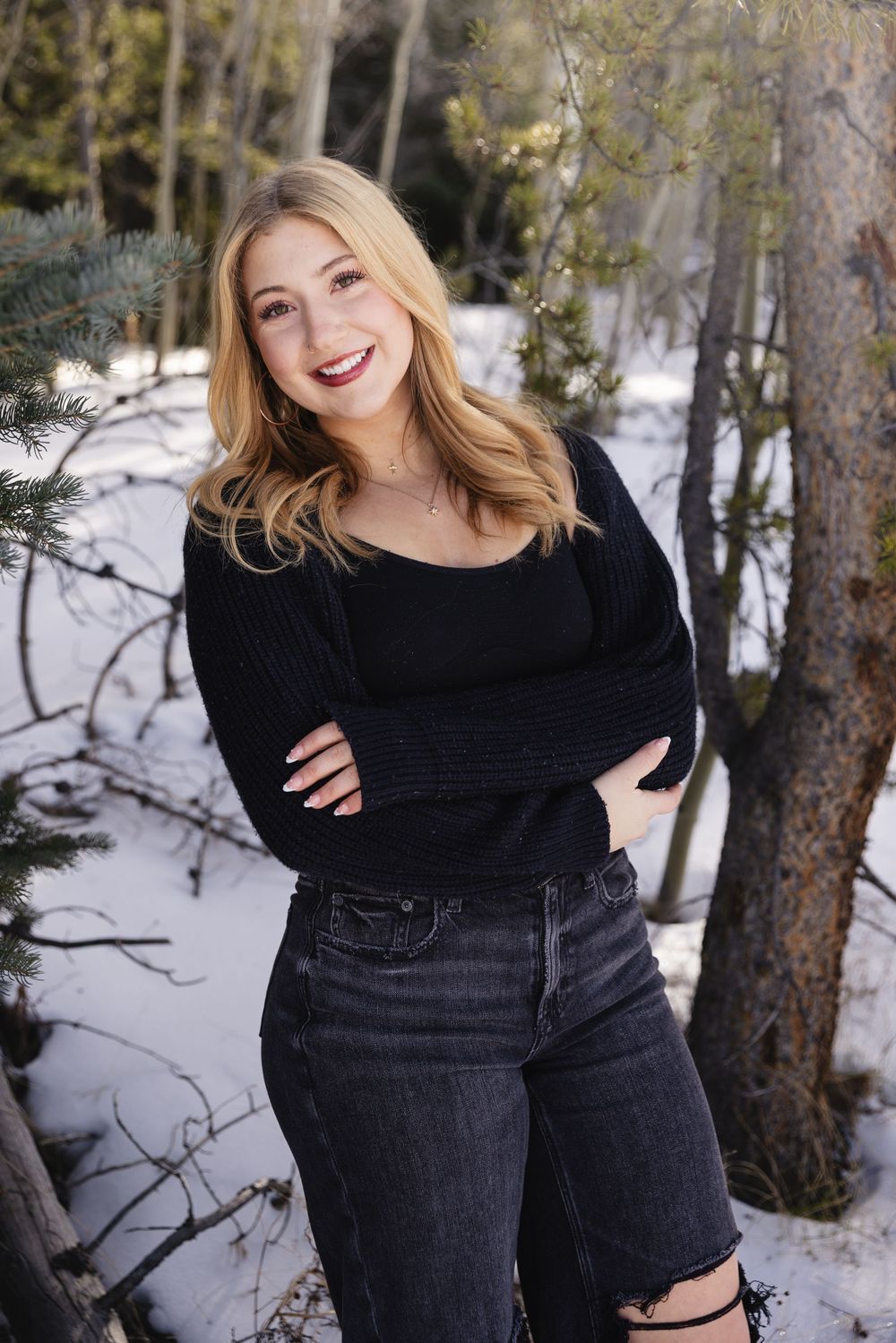 A series of winter outdoor portraits showing someone wearing a black sweater against a snowy forest backdrop.