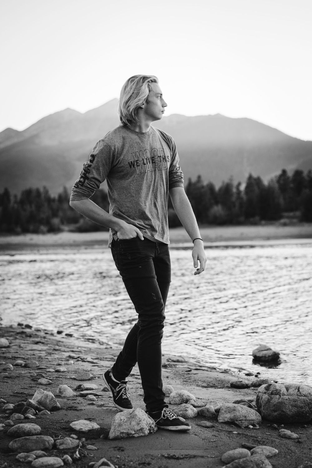 Black and white portrait by rocky mountain lake with scenic backdrop.