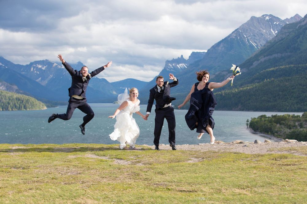 Wedding party jumping joyfully with mountains and lake in the background.