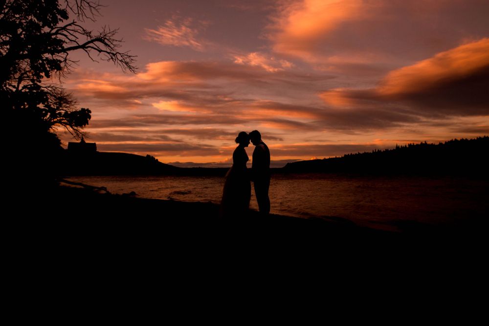 Silhouetted couple against a dramatic orange and purple sunset sky.