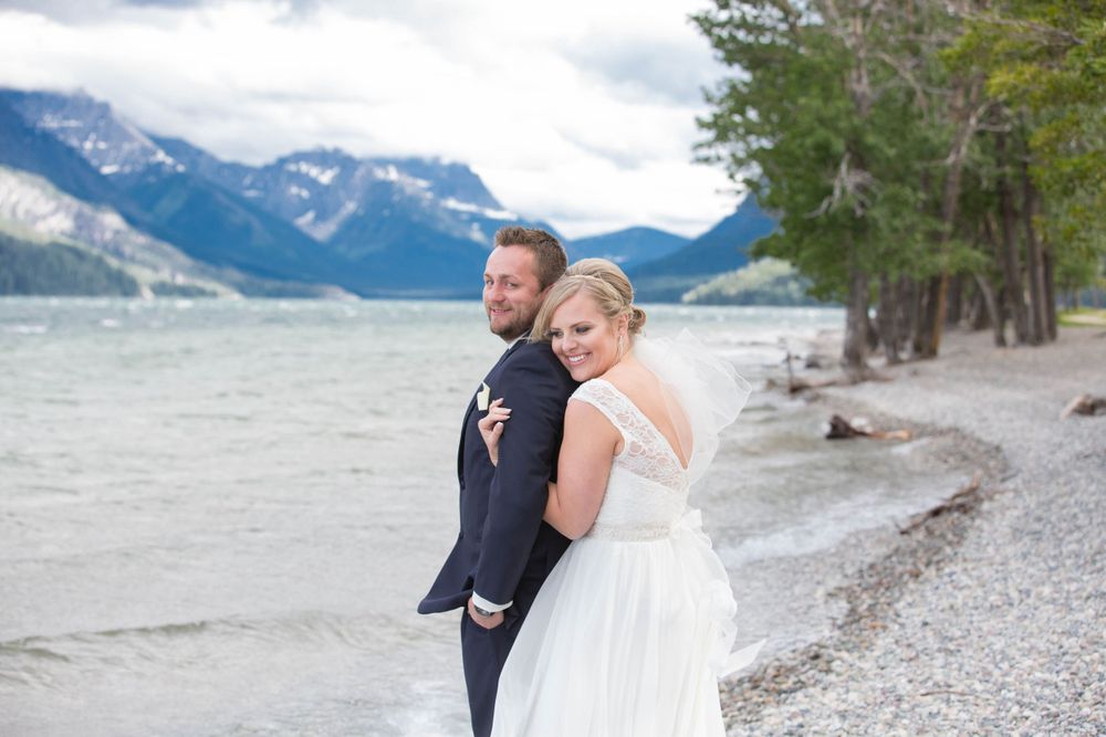 Romantic beach wedding photos with mountains and lake in the background.