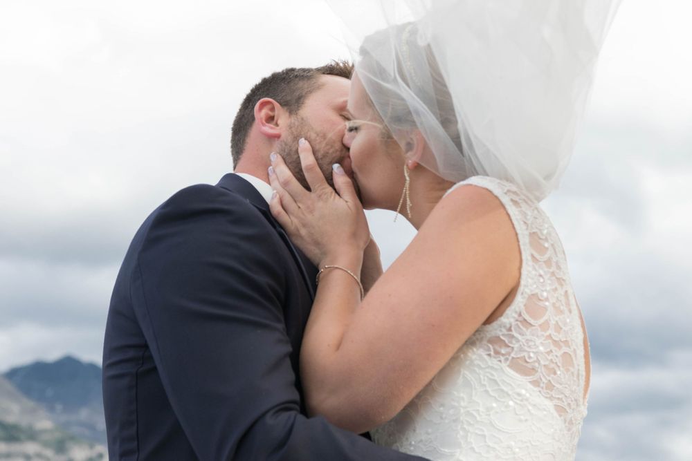 Elegant wedding portraits captured against cloudy mountain landscape.