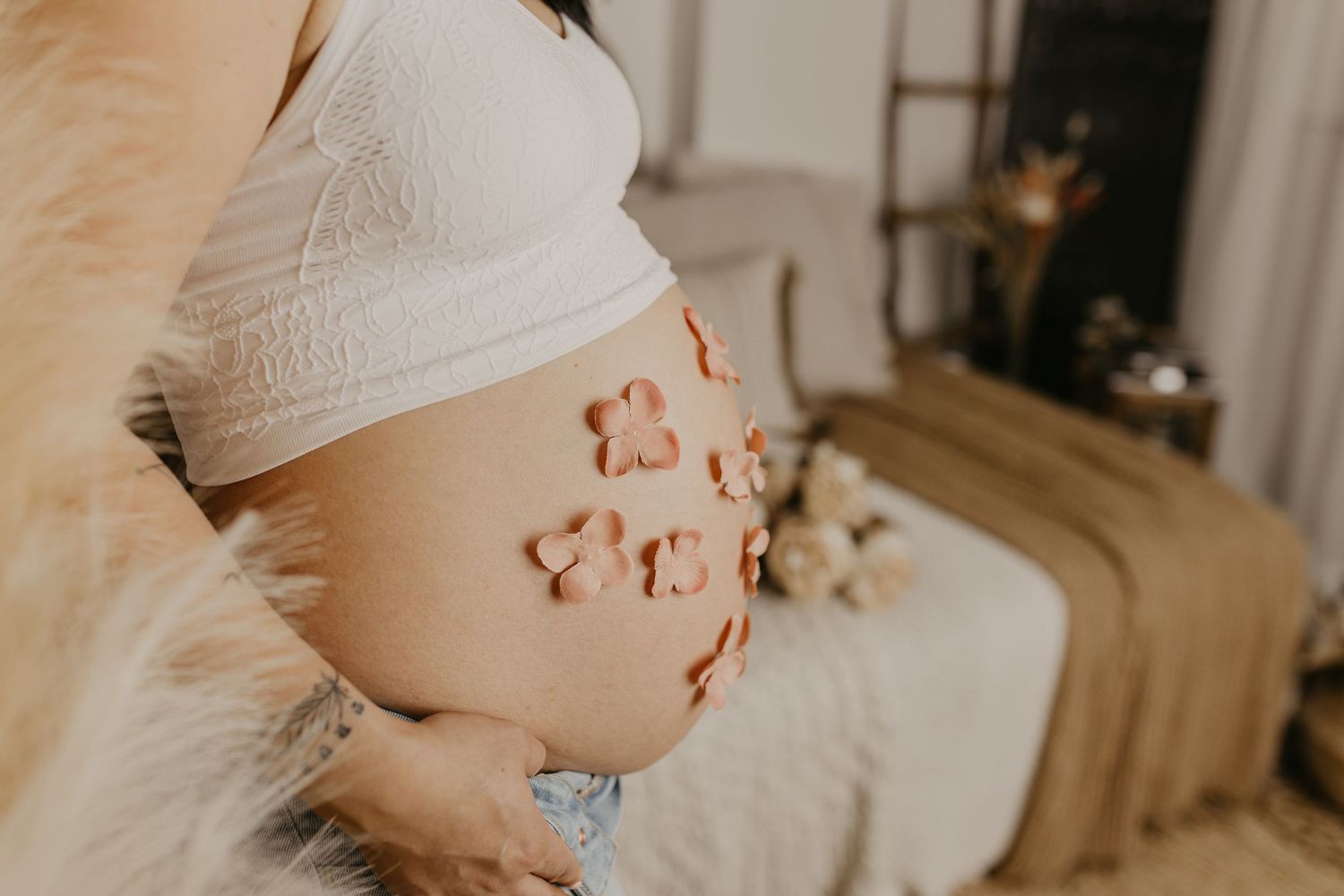 Close up of pregnant belly with heart-shaped henna designs in artistic maternity photo.