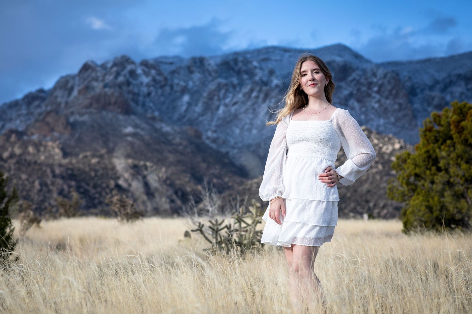 Beautiful outdoor senior portrait photography; woman in a white dress in New Mexico landscape; Sandia Mountains; Clarissa Anello