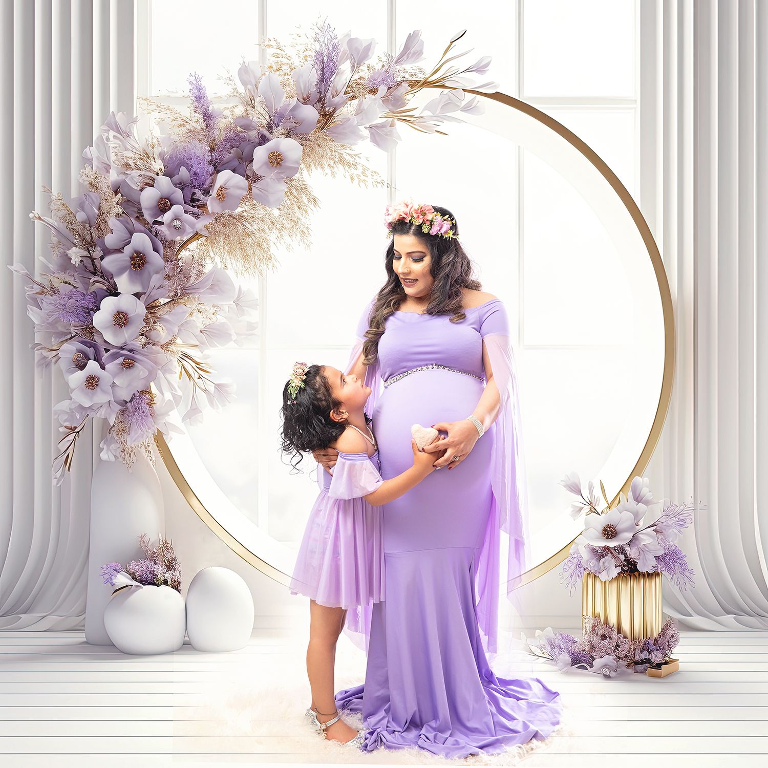 Pregnant woman in lavender gown with daughter in matching dress posed before floral hoop backdrop.