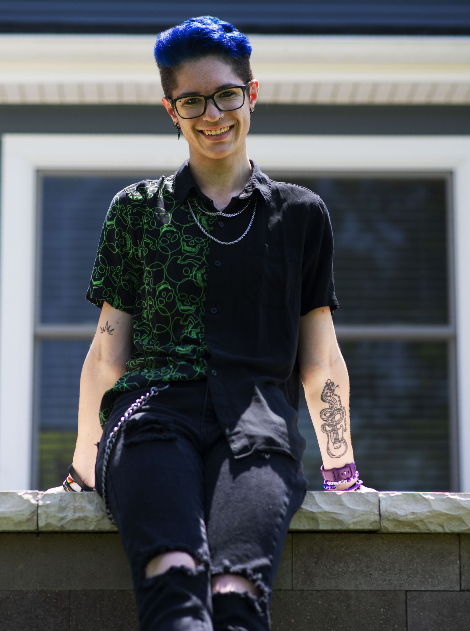 AJ sitting on a stone ledge and smiling
