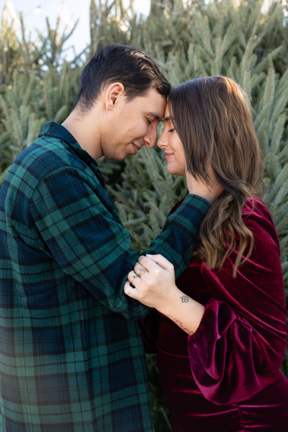 Romantic couple in plaid shirt and burgundy sweater share intimate moments against evergreen trees in progression of photos.