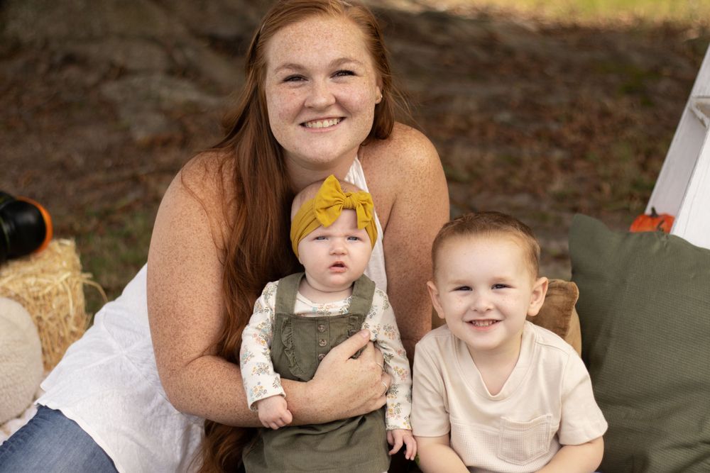 A heartwarming fall photo session featuring three people sitting together outdoors.