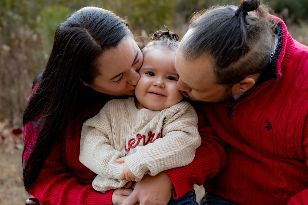 A series of candid family photos showing tender moments between parents and child in matching red and white outfits.
