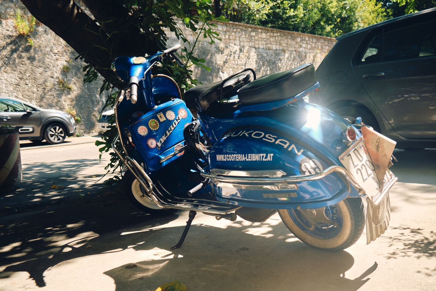 Blue sports motorcycle parked in shaded parking area with sunlight streaming through.