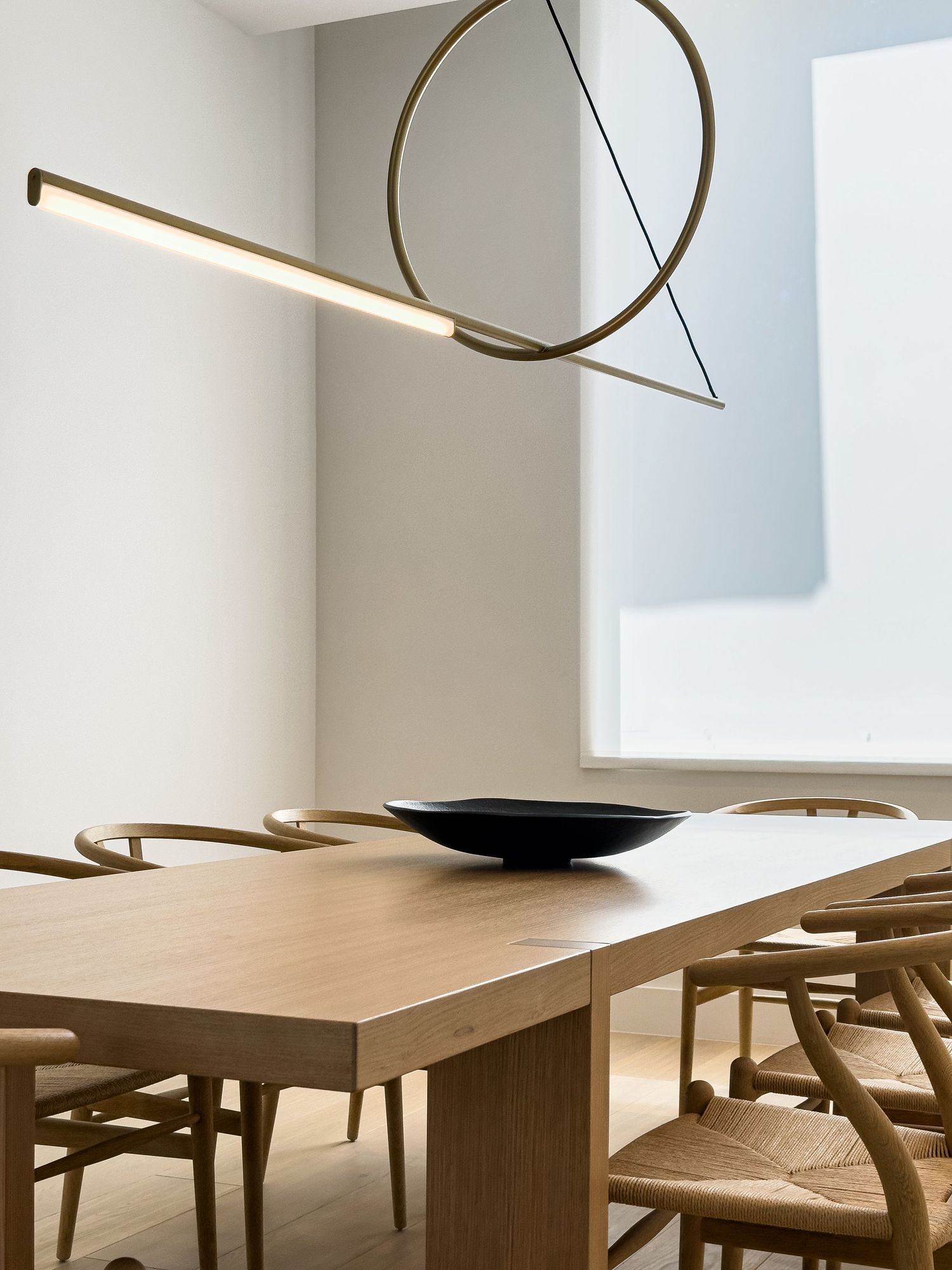 Modern dining room interior with wooden table and minimalist pendant lighting.