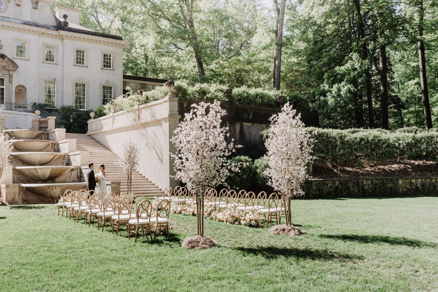 Elegant wedding reception table setting with white tablecloth, gold chairs, and delicate floral centerpieces.