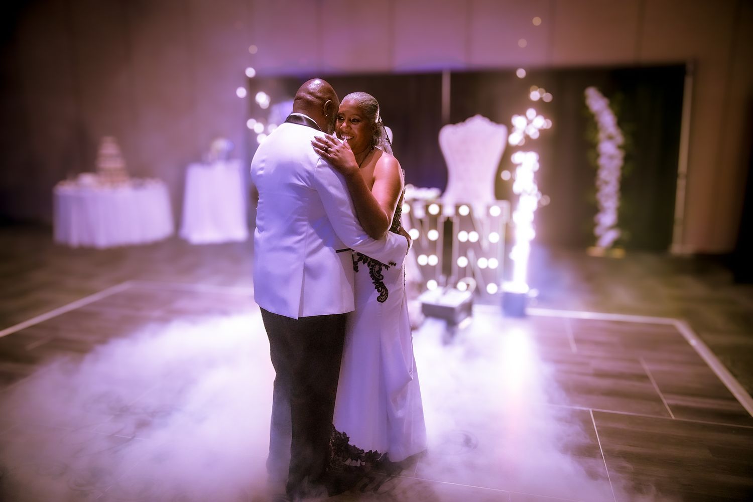 Intimate wedding dance moment captured with purple lighting and decorative elements.