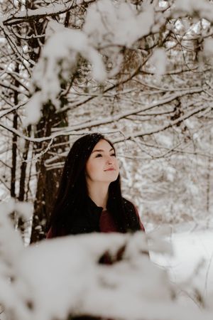 Winter portrait with person looking up at snow-covered tree branches.