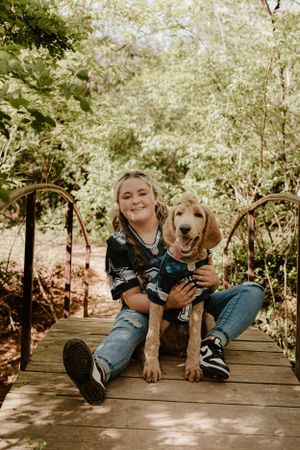 A sweet moment with a golden retriever puppy on a wooden bridge in a garden setting.