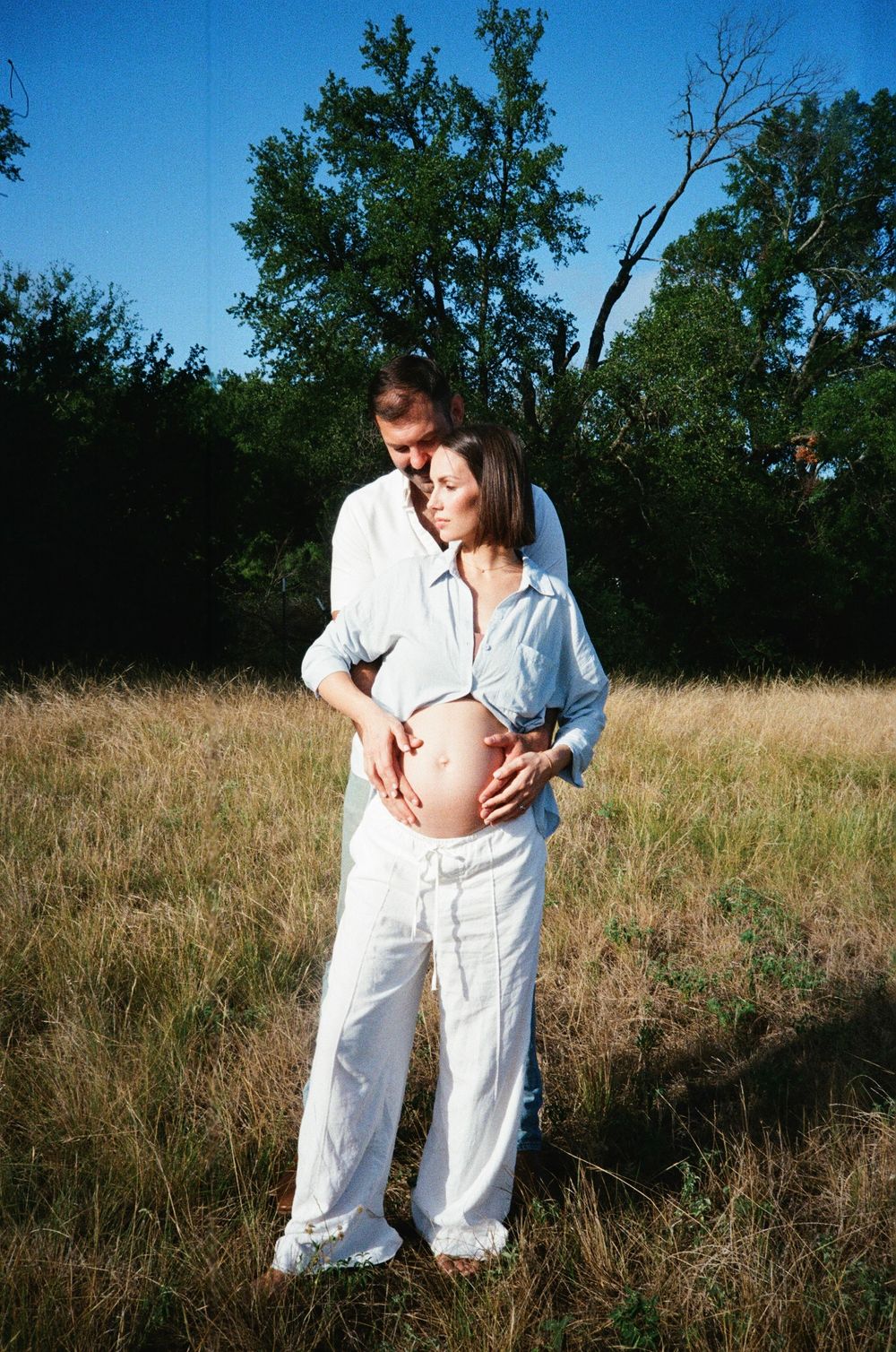 A couple shares an intimate moment in a golden field at sunset.