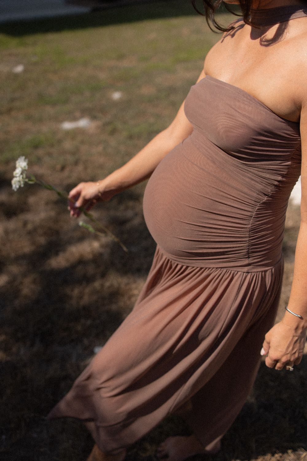 Close up of pregnant belly in flowing brown maternity dress.