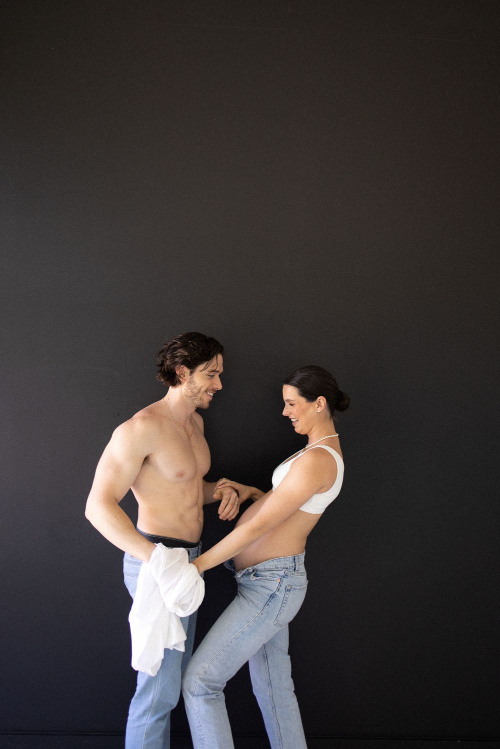 Artistic studio portrait against dark background showing playful interaction.