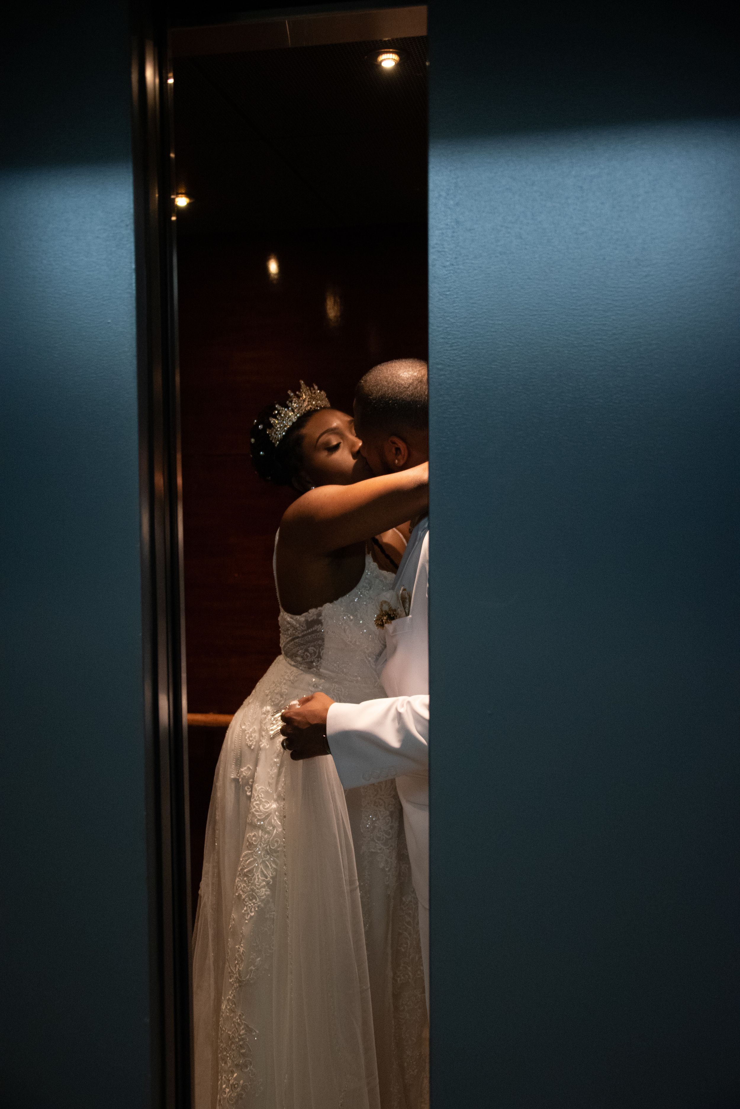 Wedding photography of couple in elevator stealing a kiss