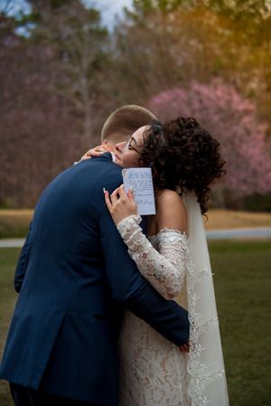 Bride and groom, hugging while holding vowels outdoors