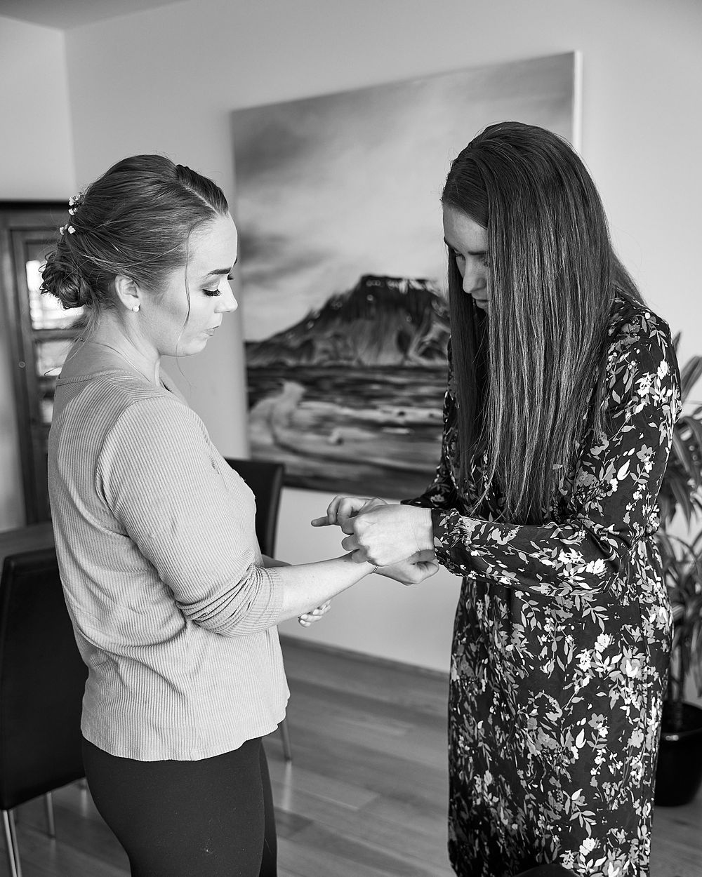 Two women reviewing paperwork together in front of mountain artwork in modern interior.