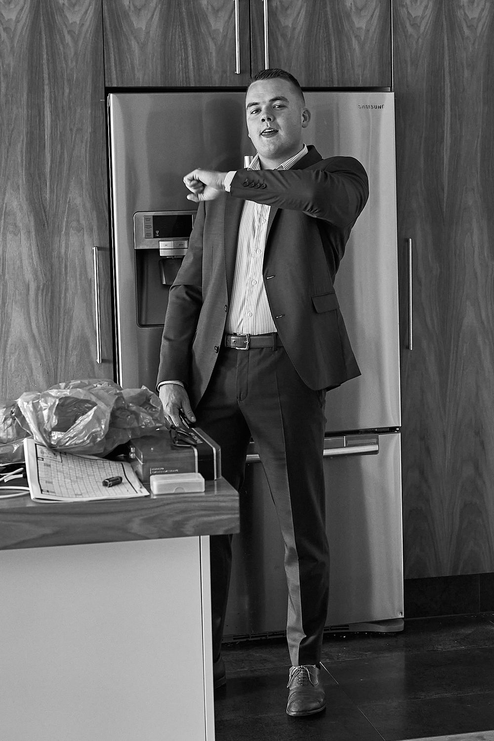 Person in business attire poses against wood paneled wall in black and white photography.