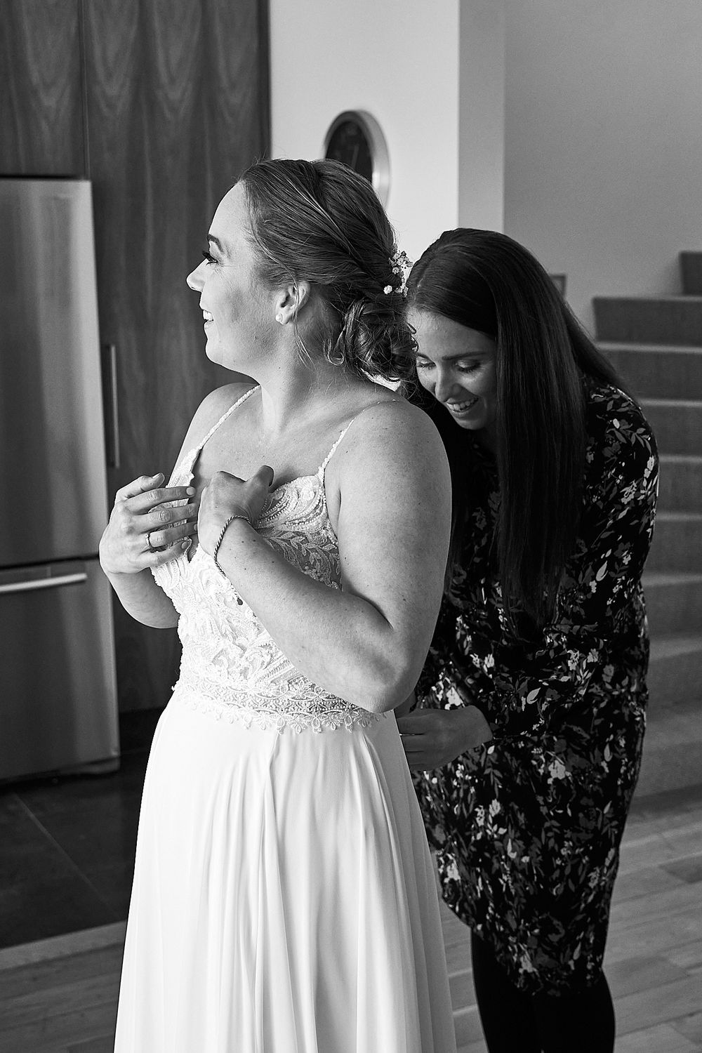 Black and white photo of wedding dress fitting with final adjustments being made.