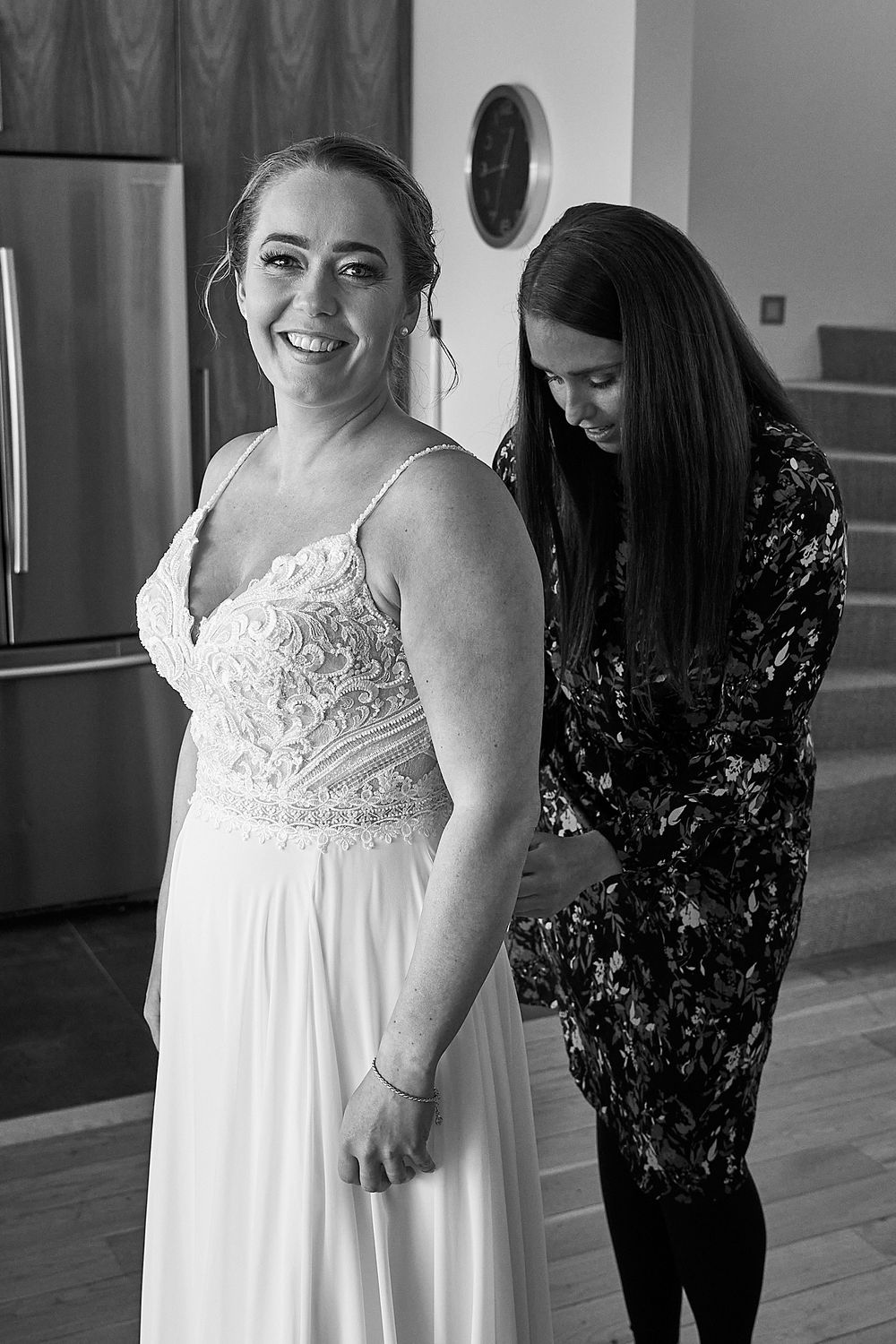Candid moment during bridal fitting with seamstress adjusting white lace wedding gown.