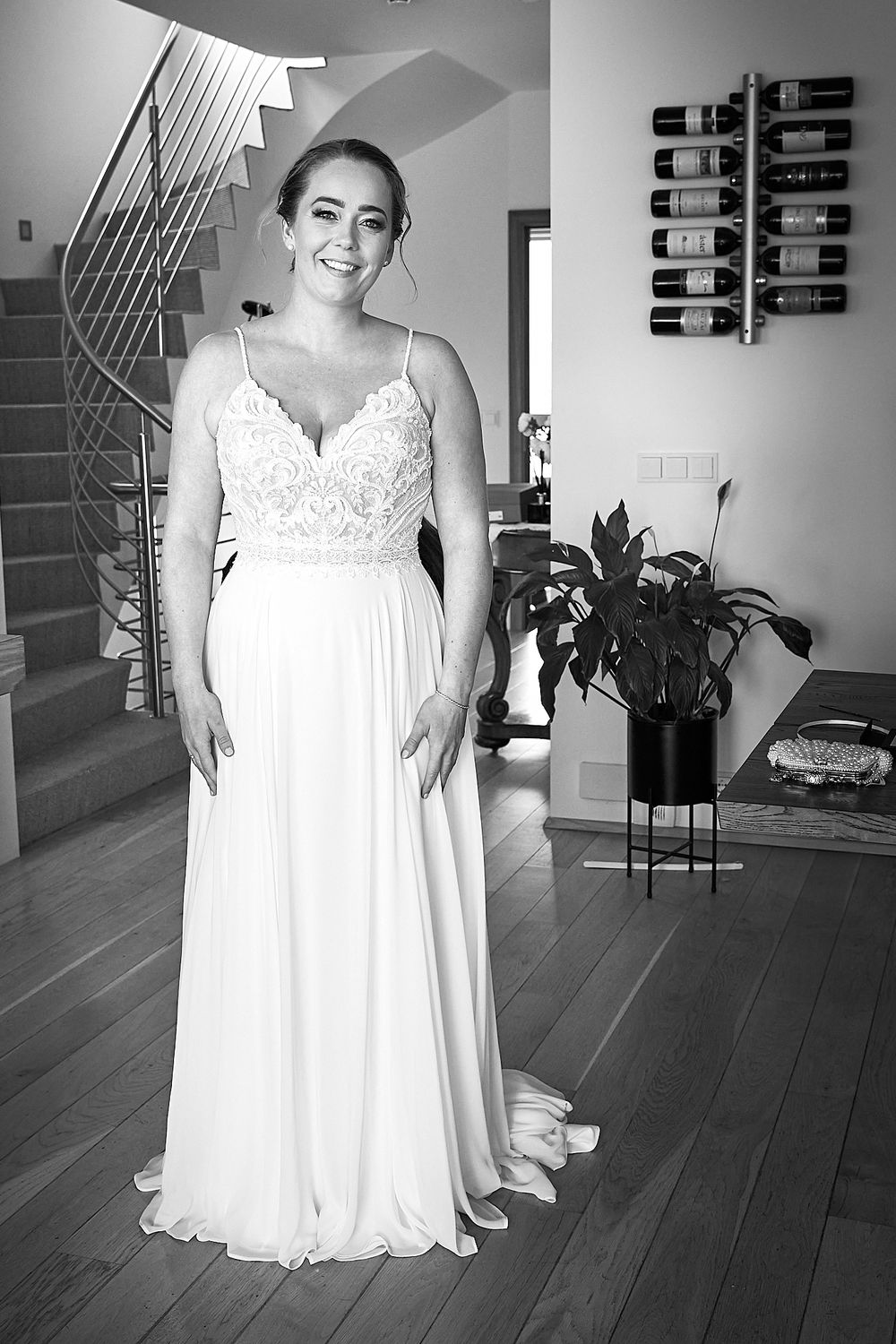 Black and white photo of bridal gown with intricate lace bodice and flowing skirt in modern setting.