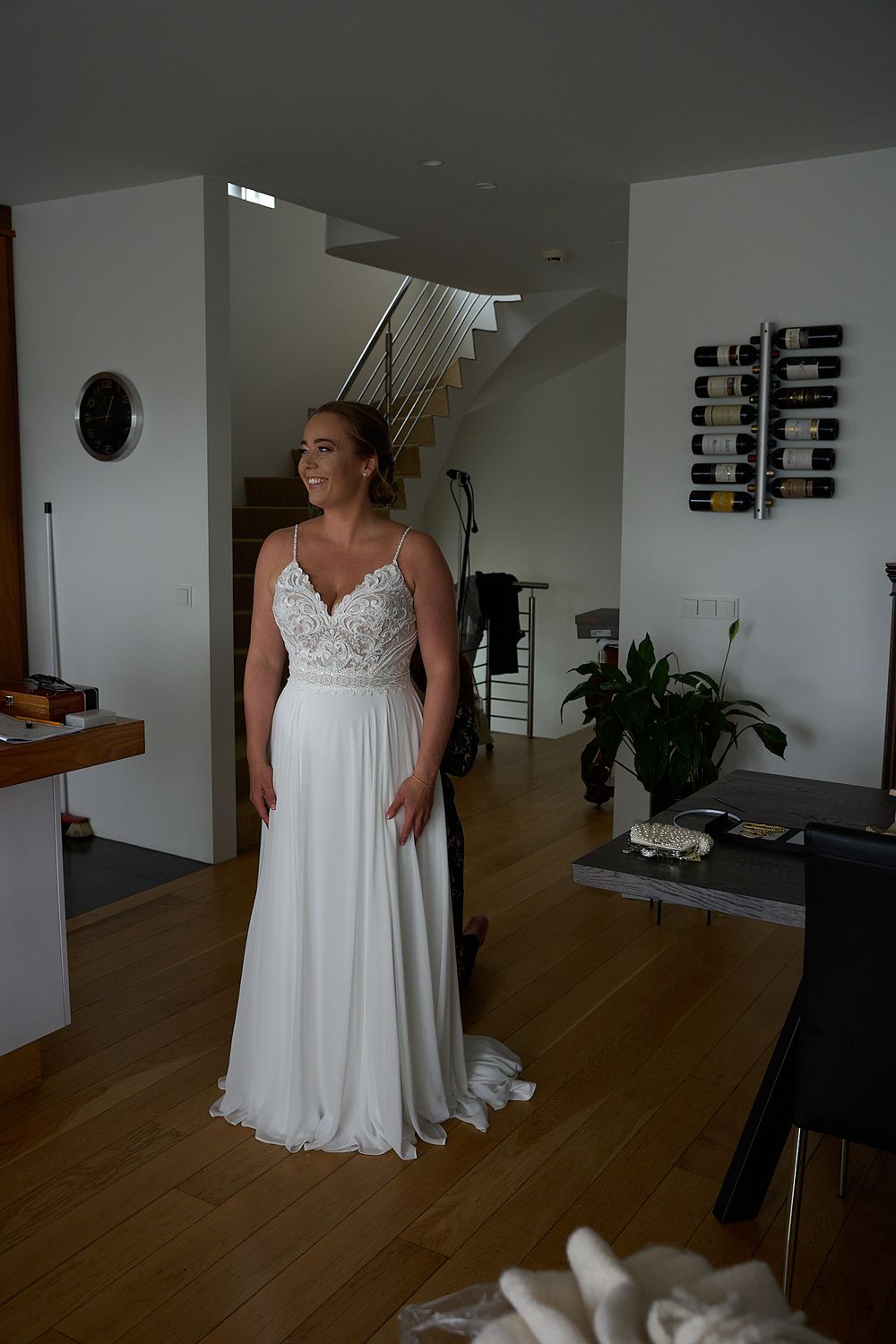 Wedding dress captured in natural light showing detailed lace bodice and flowing white skirt against wood floors.