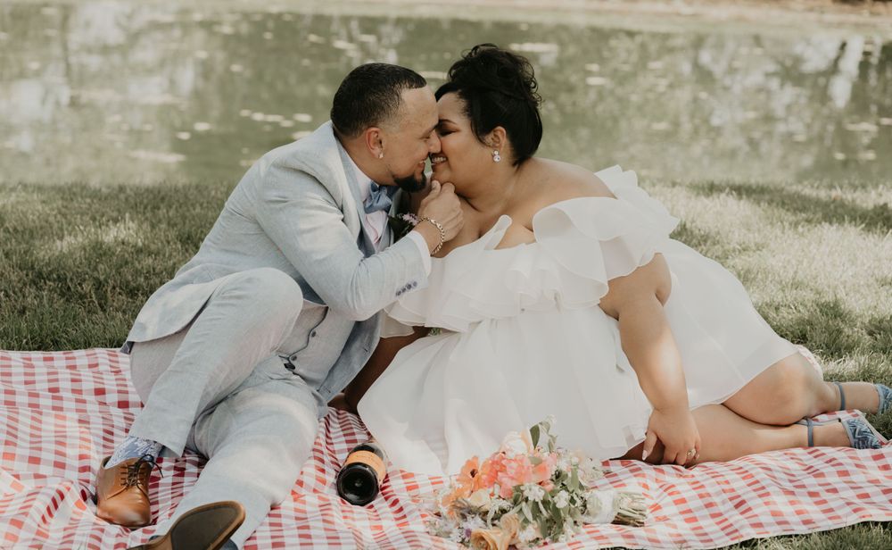 Intimate moment between newlyweds on a picnic blanket outdoors.