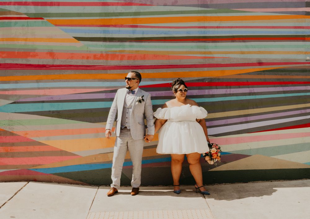 Wedding couple posing together against a bright geometric painted wall.