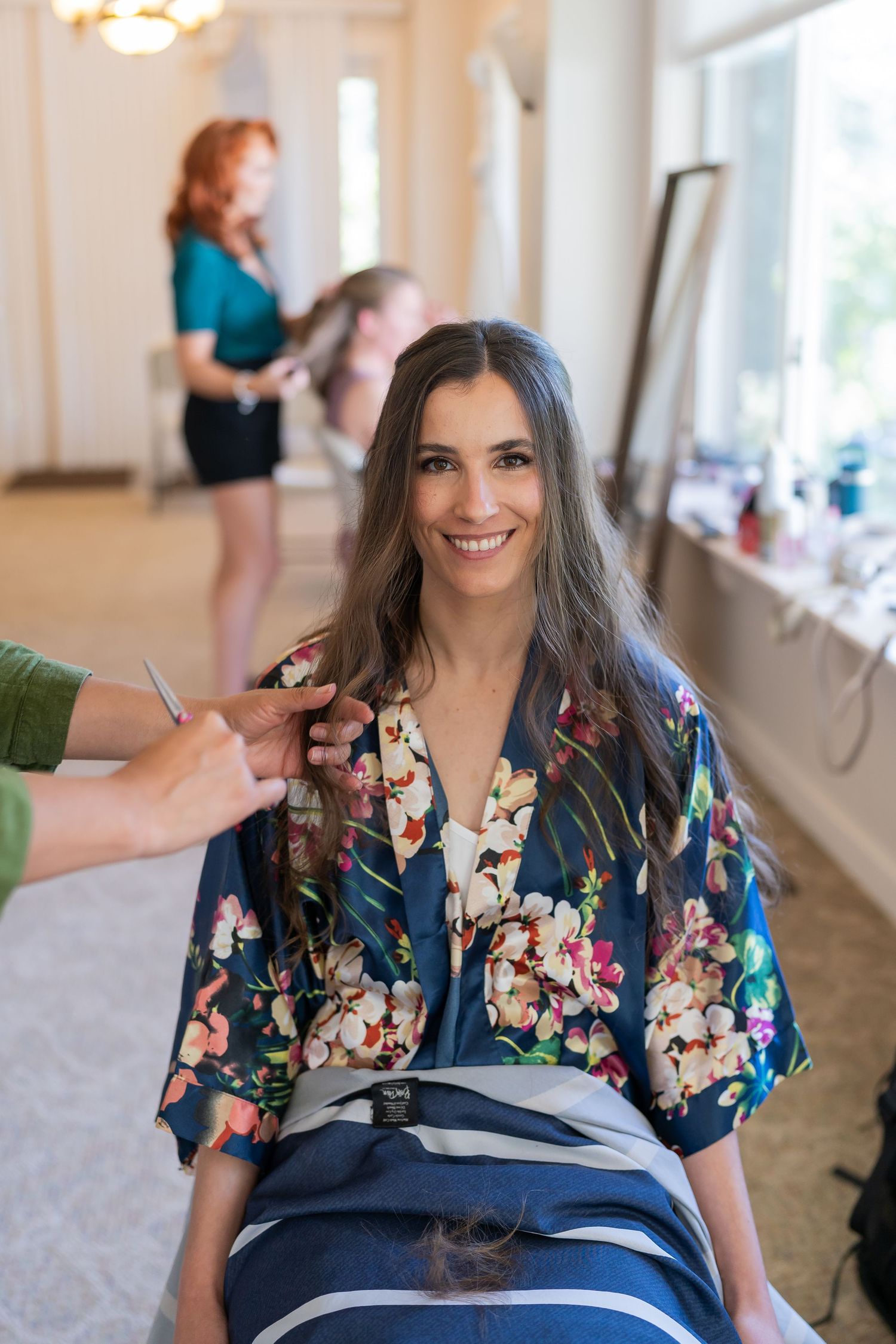 Person getting hair styled in floral robe during wedding preparation.