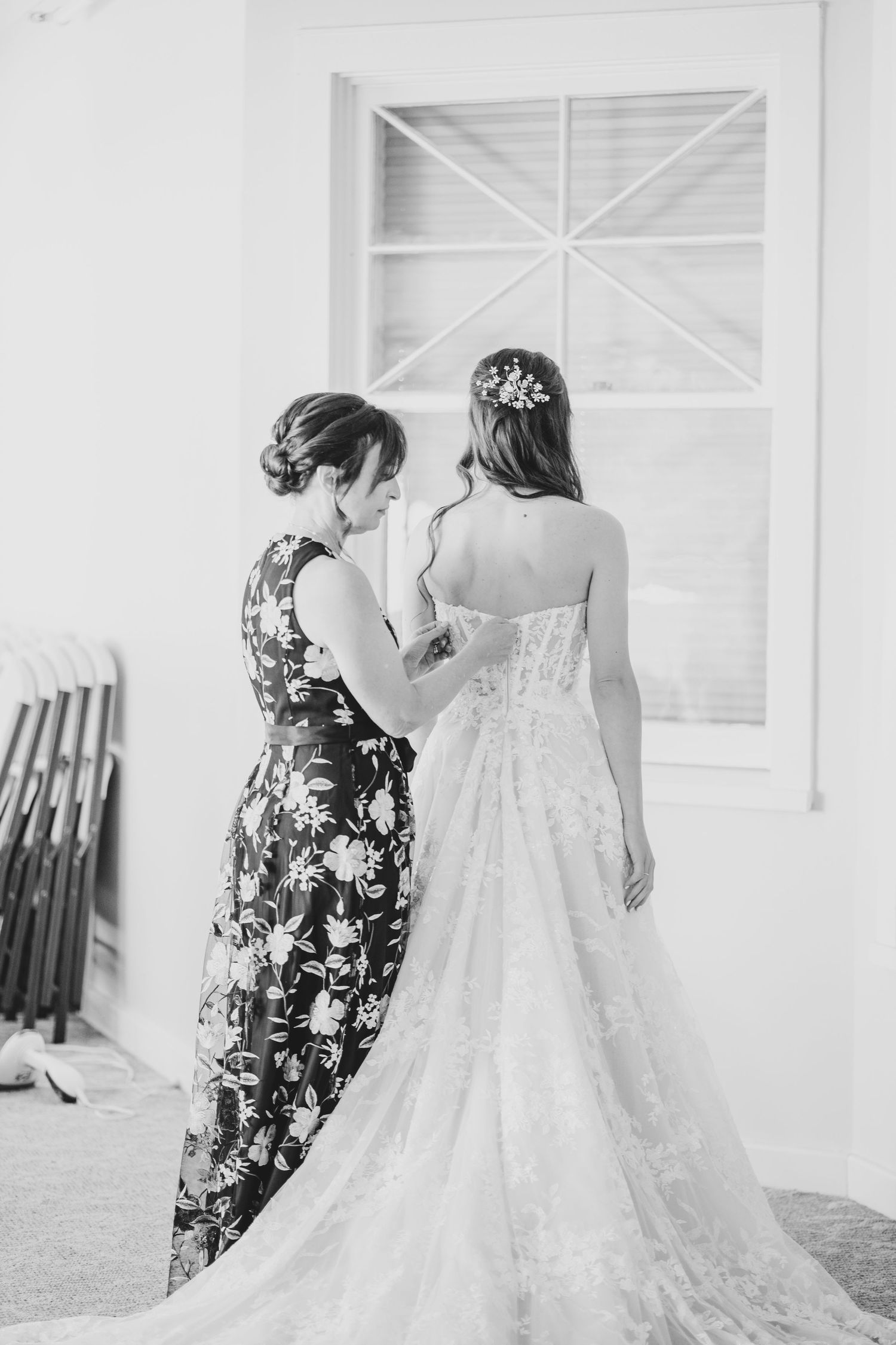Helper assisting with dress details and final touches before the ceremony.