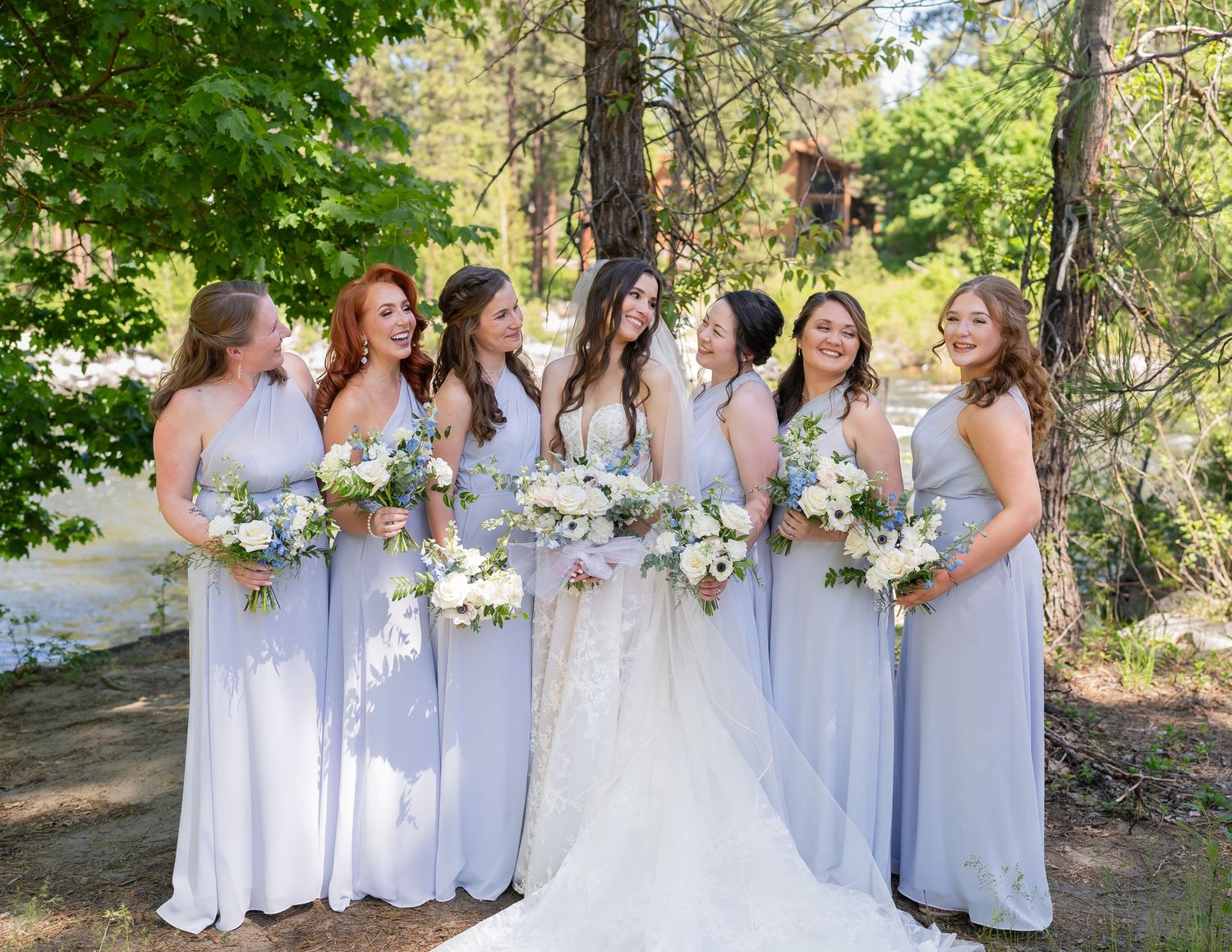 Bridal party in light purple dresses holding bouquets outdoors.