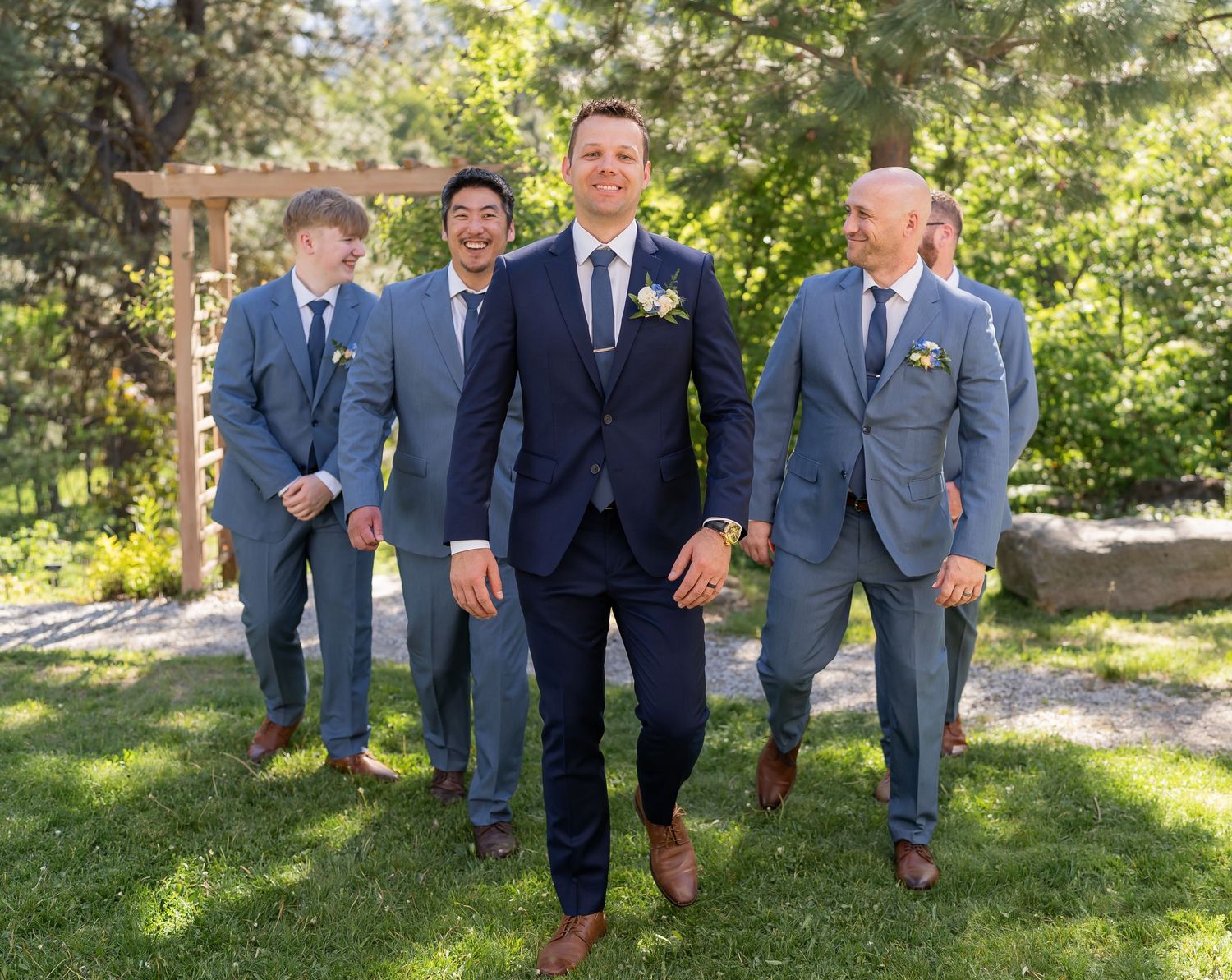 Groomsmen in mix of navy and gray suits posing outdoors.