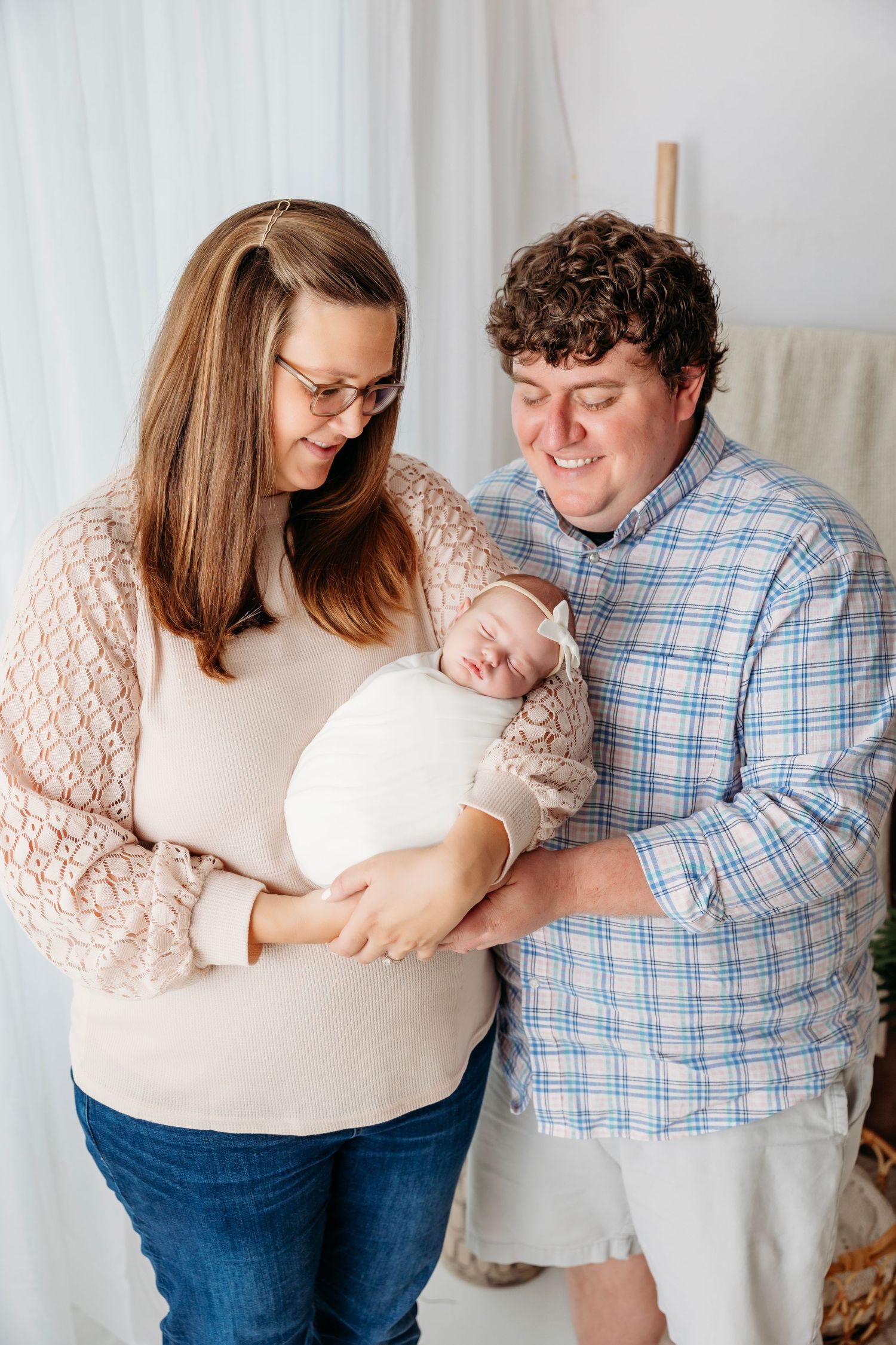 intimate family portraits showing parents holding and bonding with their newborn baby against a light backdrop.  Middle TN photographer