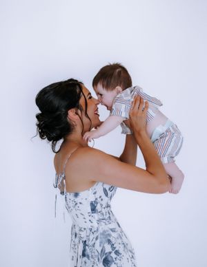 A tender moment captured in white studio setting with floral dress and glass bottle.