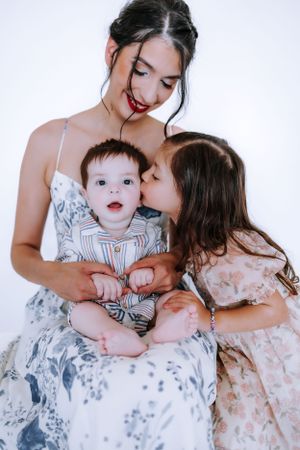 Sweet family portrait with children in soft floral dresses against white backdrop.